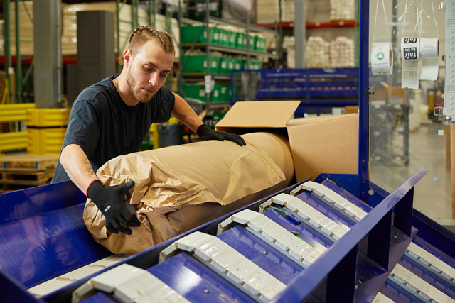 Man loading mattress in paper wrapping into box