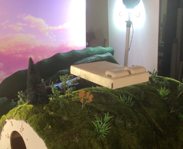 a model Earthfoam mattress and pillows floating above a green landscape
