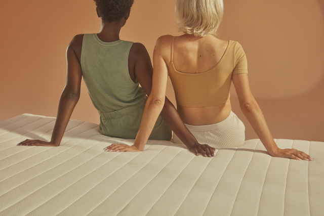 Two women sitting on edge of bed